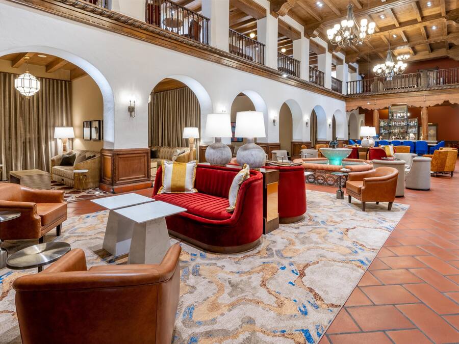 A spacious lobby with leather armchairs, a red sofa, and a bar area.