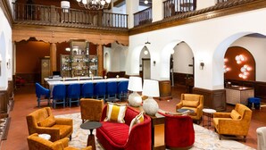 A spacious lobby with a bar area, multiple seating options including sofas and armchairs, and a high ceiling with a balcony. - Hotel Andaluz Albuquerque, Curio Collection by Hilton (Albuquerque)