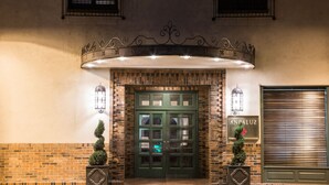 A hotel entrance with a green double door, two lantern-style lights, and a sign reading "ANDALUZ".