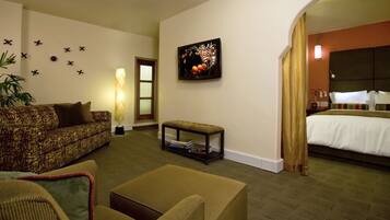 A hotel room with a sofa, a small table, a bed, and a wall-mounted TV.