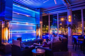 Un área de estar al aire libre con iluminación moderna y vistas a la ciudad.