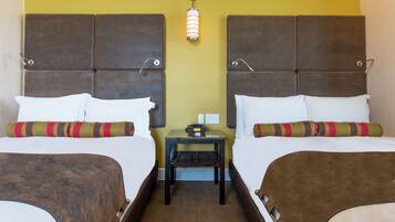 A double room with two beds, each with a headboard, a nightstand, and a lamp between the beds.