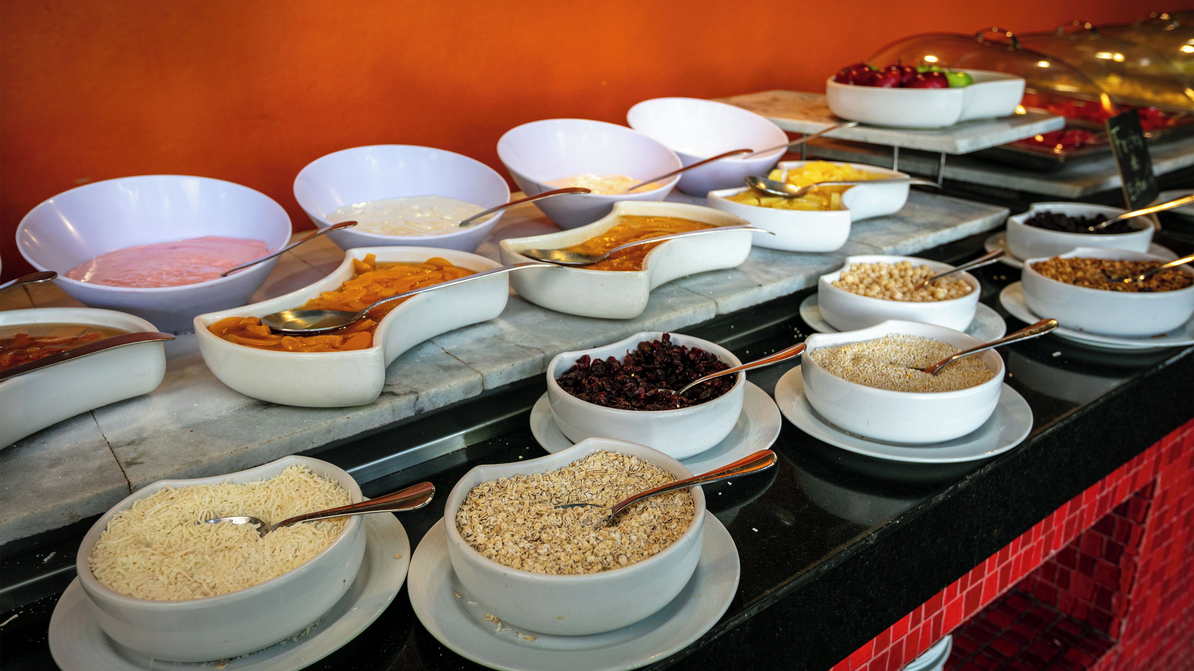 A buffet with various food items in bowls, including cereals, fruits, and other dishes.