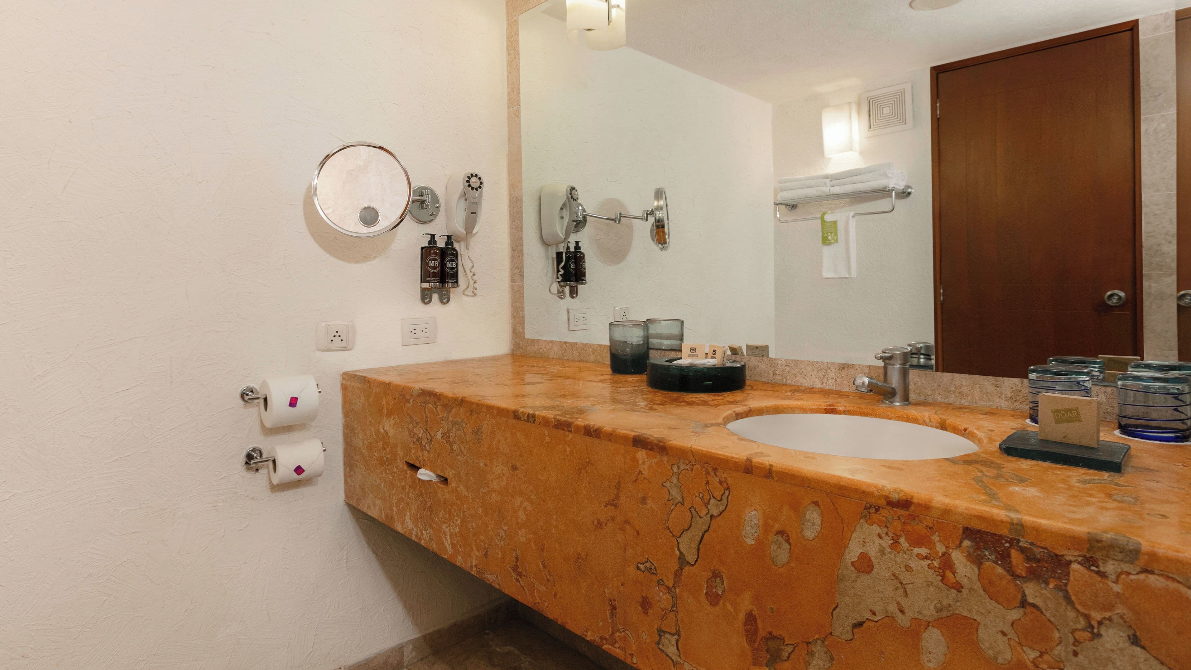 Un baño con dos lavamanos, un espejo, toallero y una puerta.