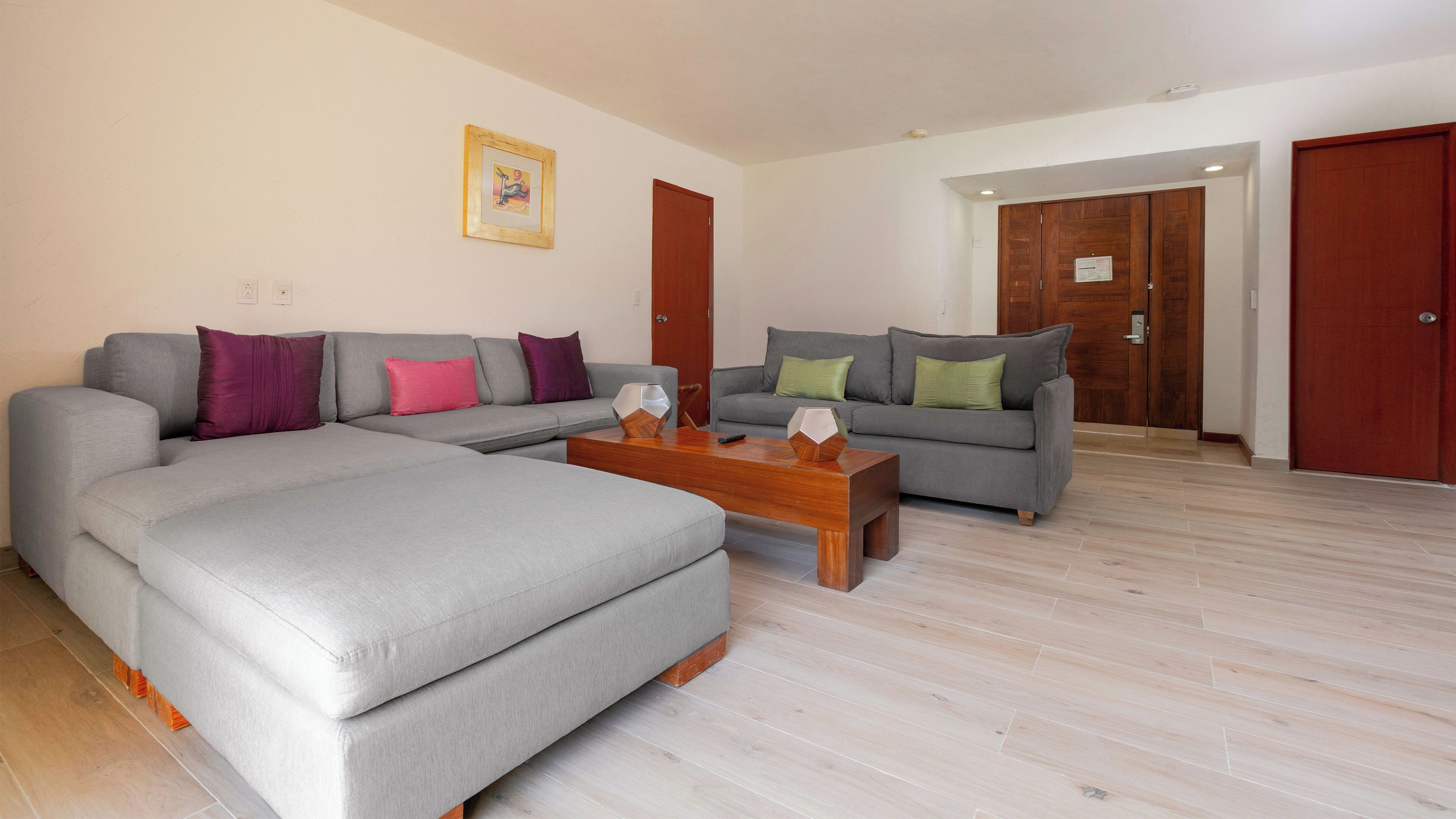 A living room with a grey sofa, a wooden coffee table, and a grey armchair.