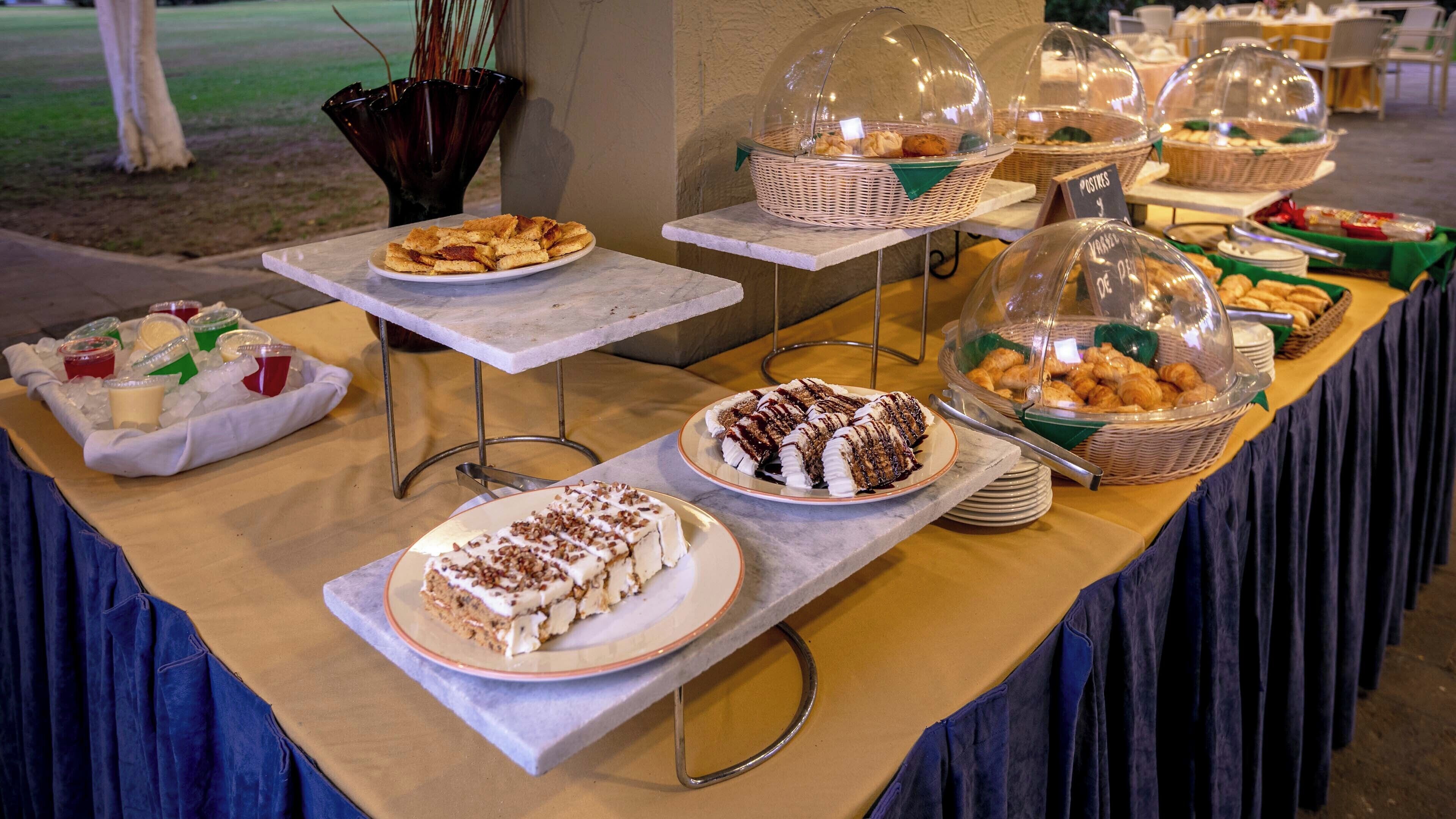 A buffet table with various food items, including cakes and pastries, covered with glass domes.