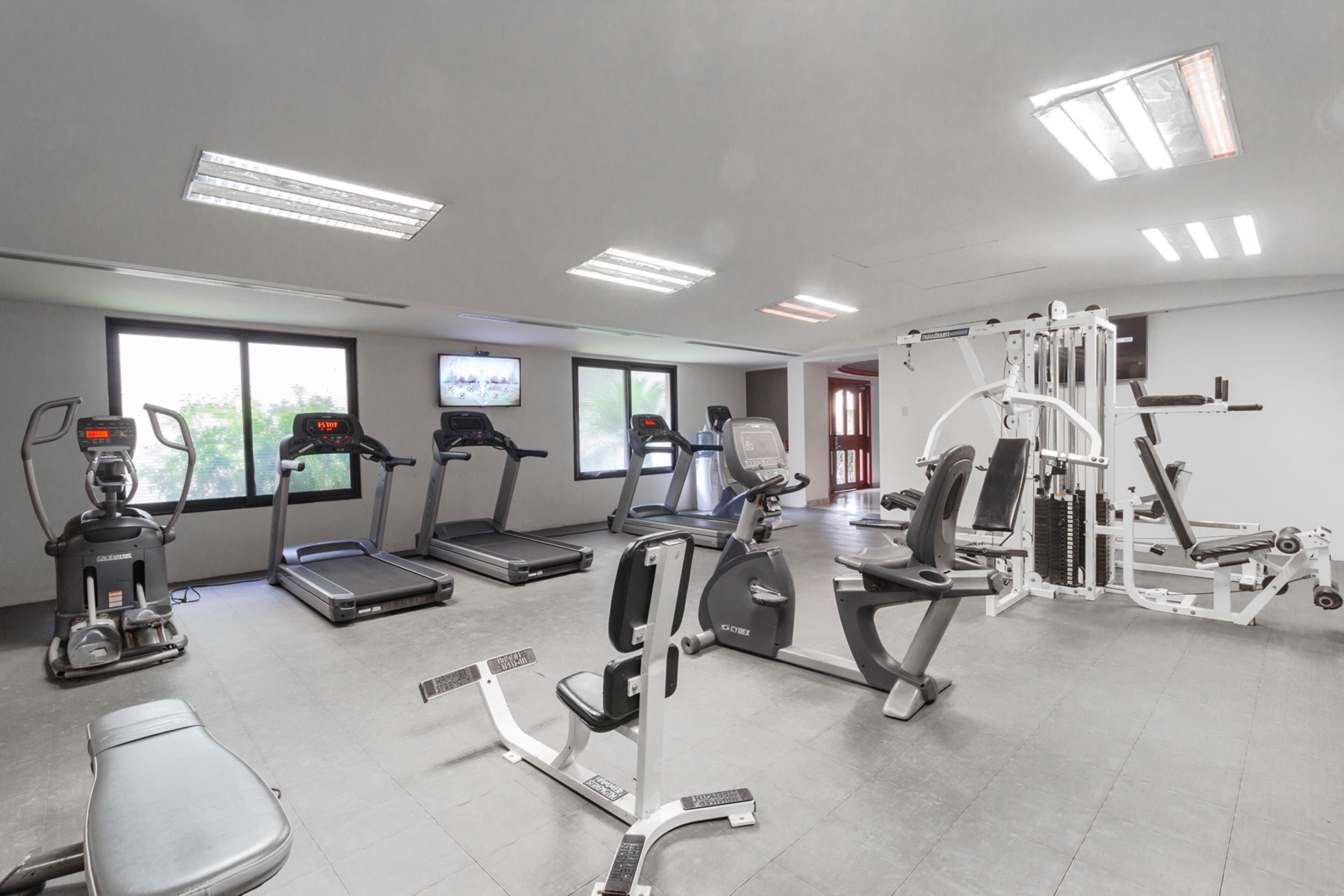 Un gimnasio con cintas de correr, elípticas y máquinas de pesas.