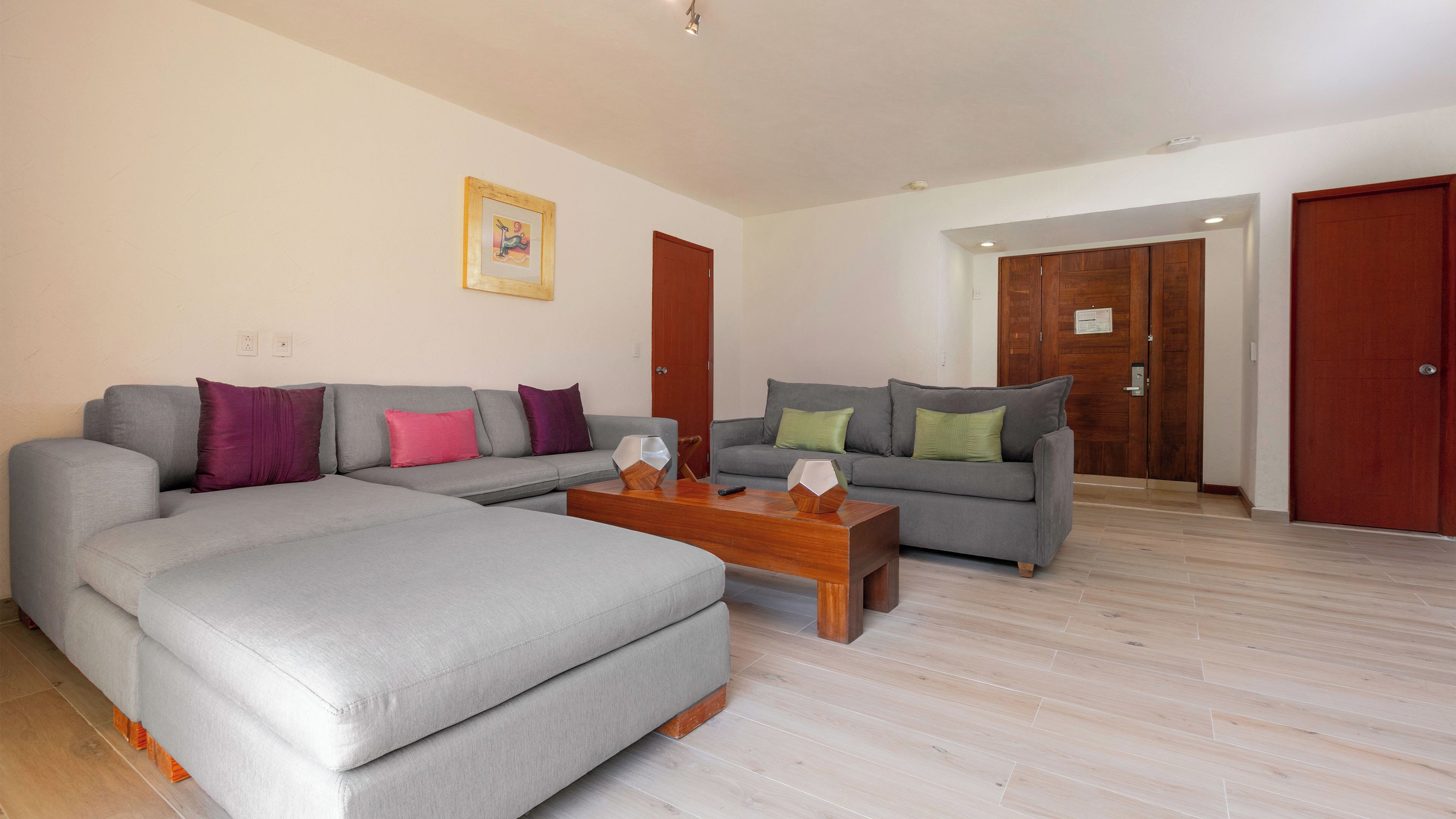 A living room with a grey sofa, a coffee table, and a wooden door.