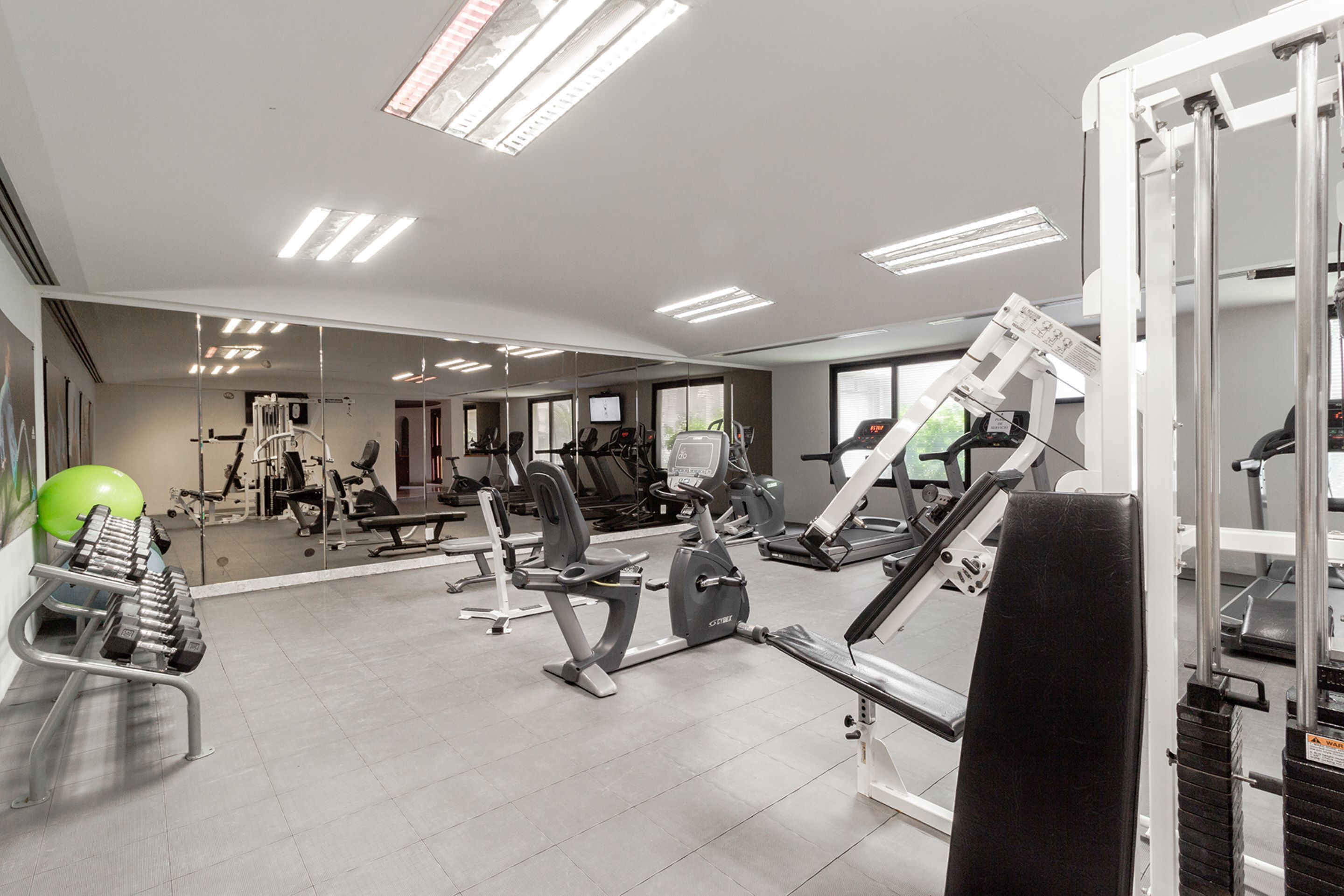 A gym with various exercise equipment, including treadmills, weight machines, and free weights.