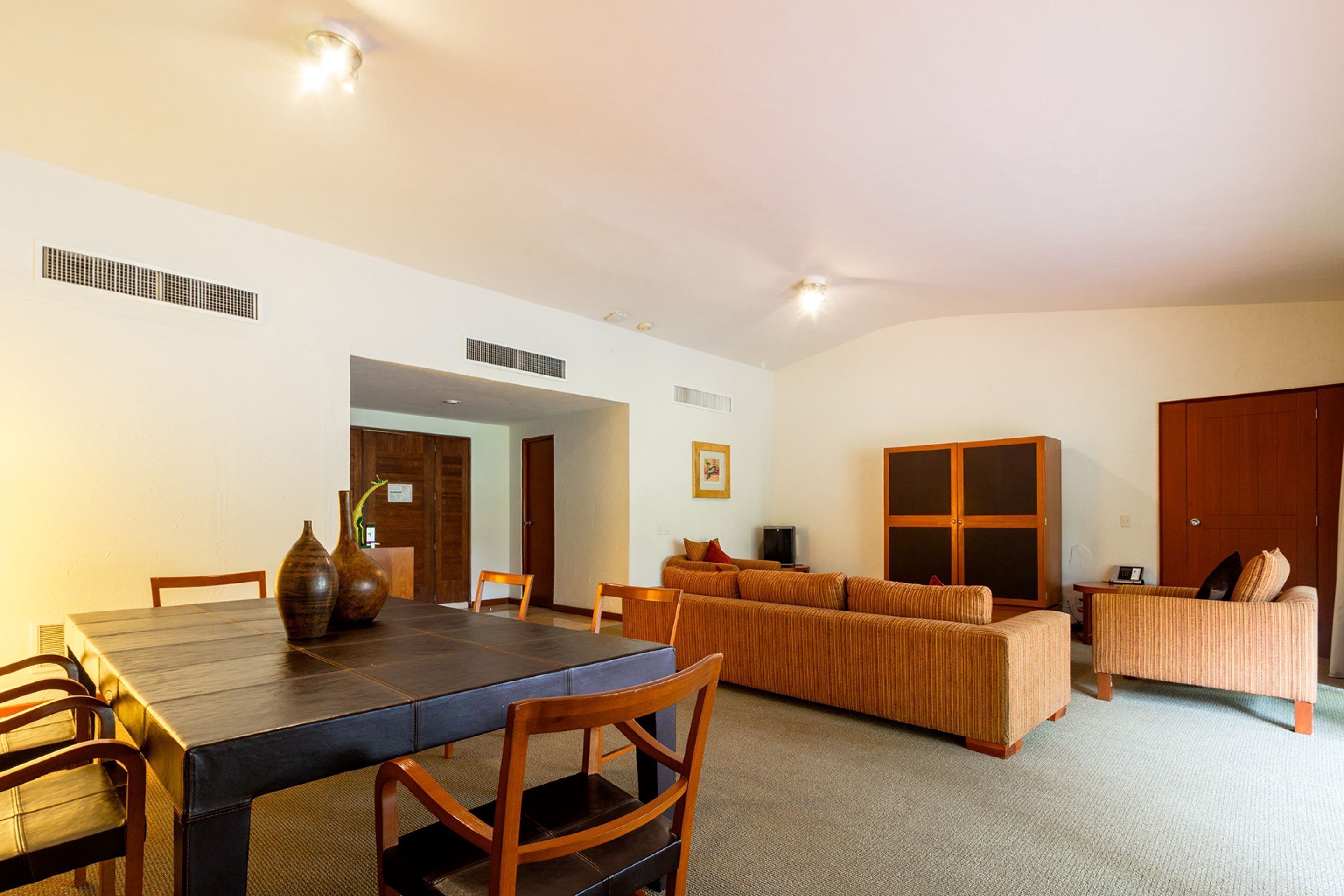 Amplia sala de estar con mesa de comedor, sillas, sofá y televisor.