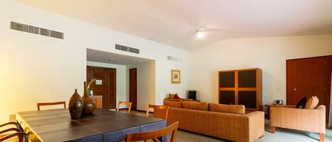 Amplia sala de estar con mesa de comedor, sillas, sofá y televisor.