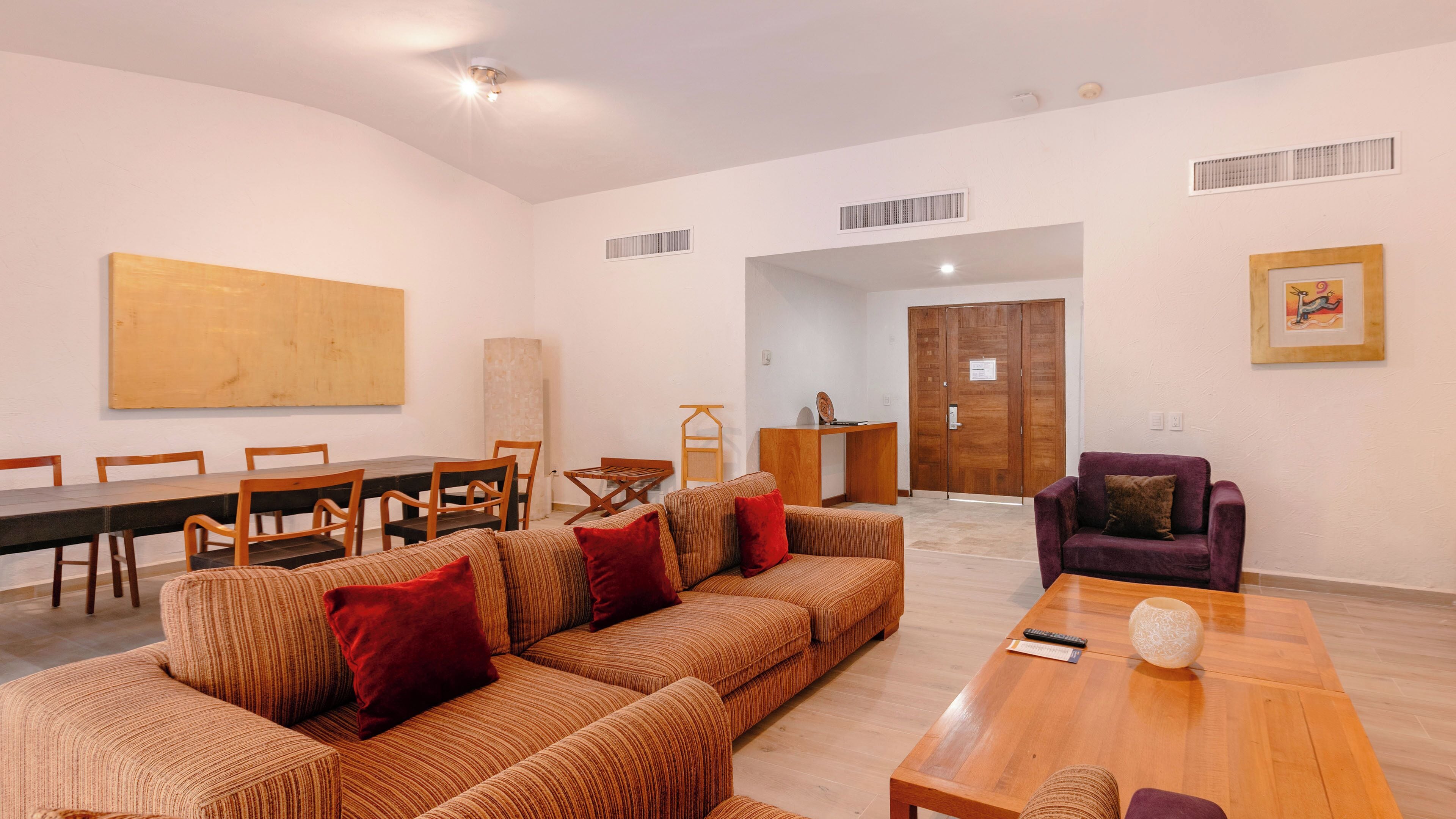A modern living room with a sofa set, a dining table with chairs, a purple armchair, and a wooden cabinet.