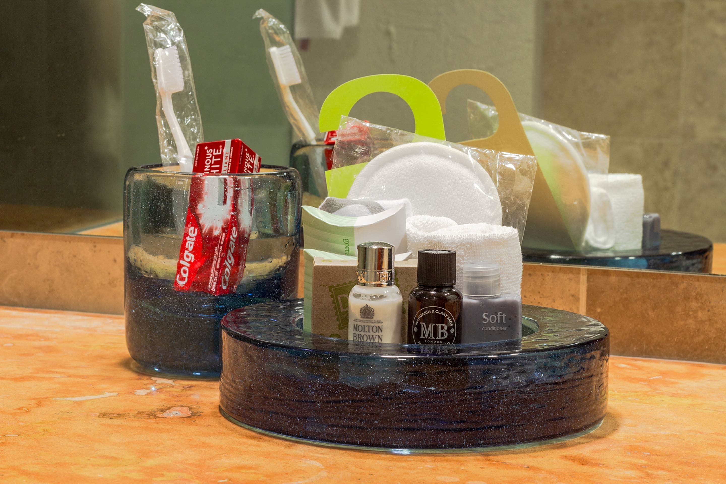 A bathroom sink area with toiletries including a toothbrush, toothpaste, and a bottle of lotion.