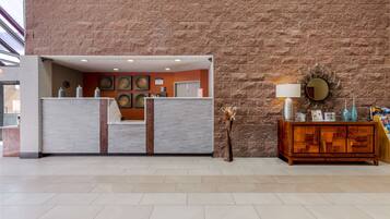 A reception area with a stone wall, a reception desk, a wooden console, and a wall-mounted mirror.