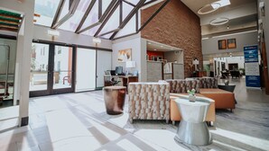 Un'ampia hall con soffitto alto, grandi finestre e diverse zone relax con divani e tavolino da caffè.