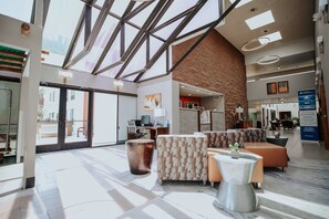 Experience the grandeur of our lobby, featuring a stunning glass ceiling, modern seating, and a unique copper sculpture.