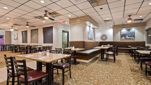 Un ristorante con diversi tavoli e posti a sedere, ventilatori a soffitto e un tappeto decorato.
