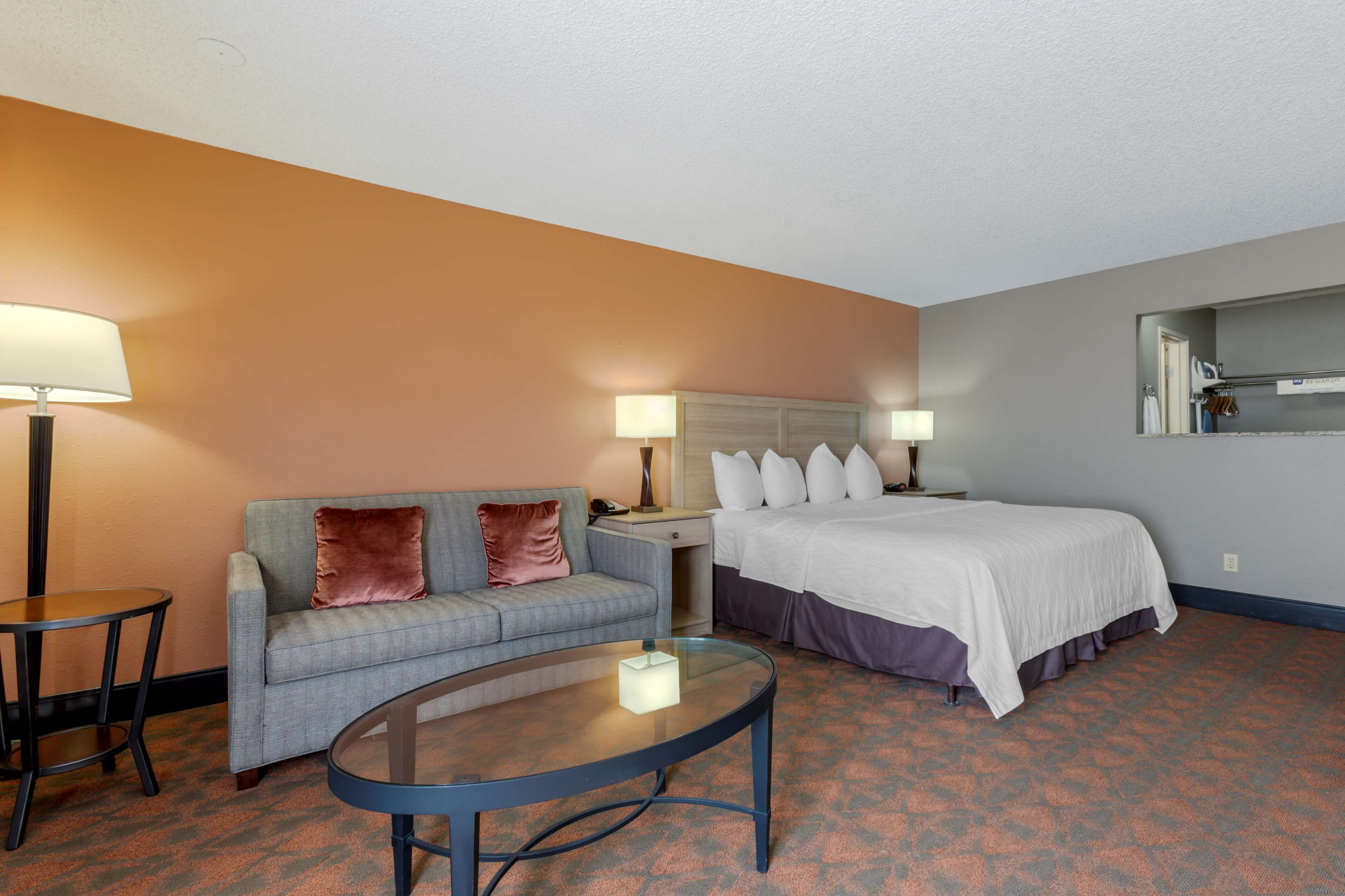 Une chambre d’hôtel avec un lit, un canapé, une petite table et deux lampes.