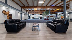 A spacious lobby with leather sofas, a central coffee table, and a large wooden ceiling.