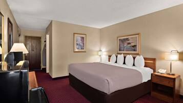 Habitación de hotel con una cama grande, dos mesitas de noche con lámparas, un escritorio con teléfono y un espejo.