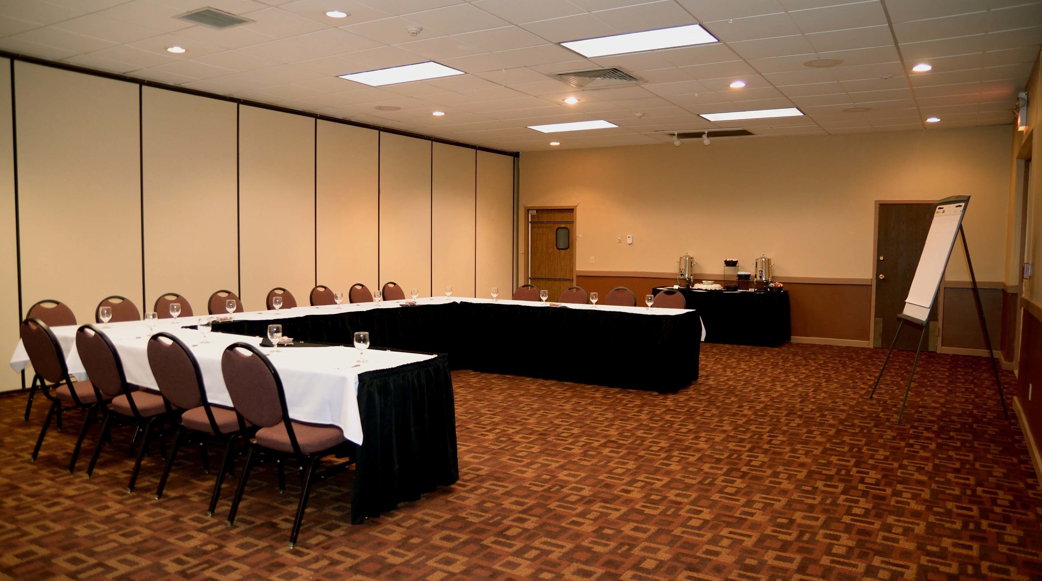 Un salón de conferencias con una larga mesa, sillas, una pizarra y una zona de bufé.