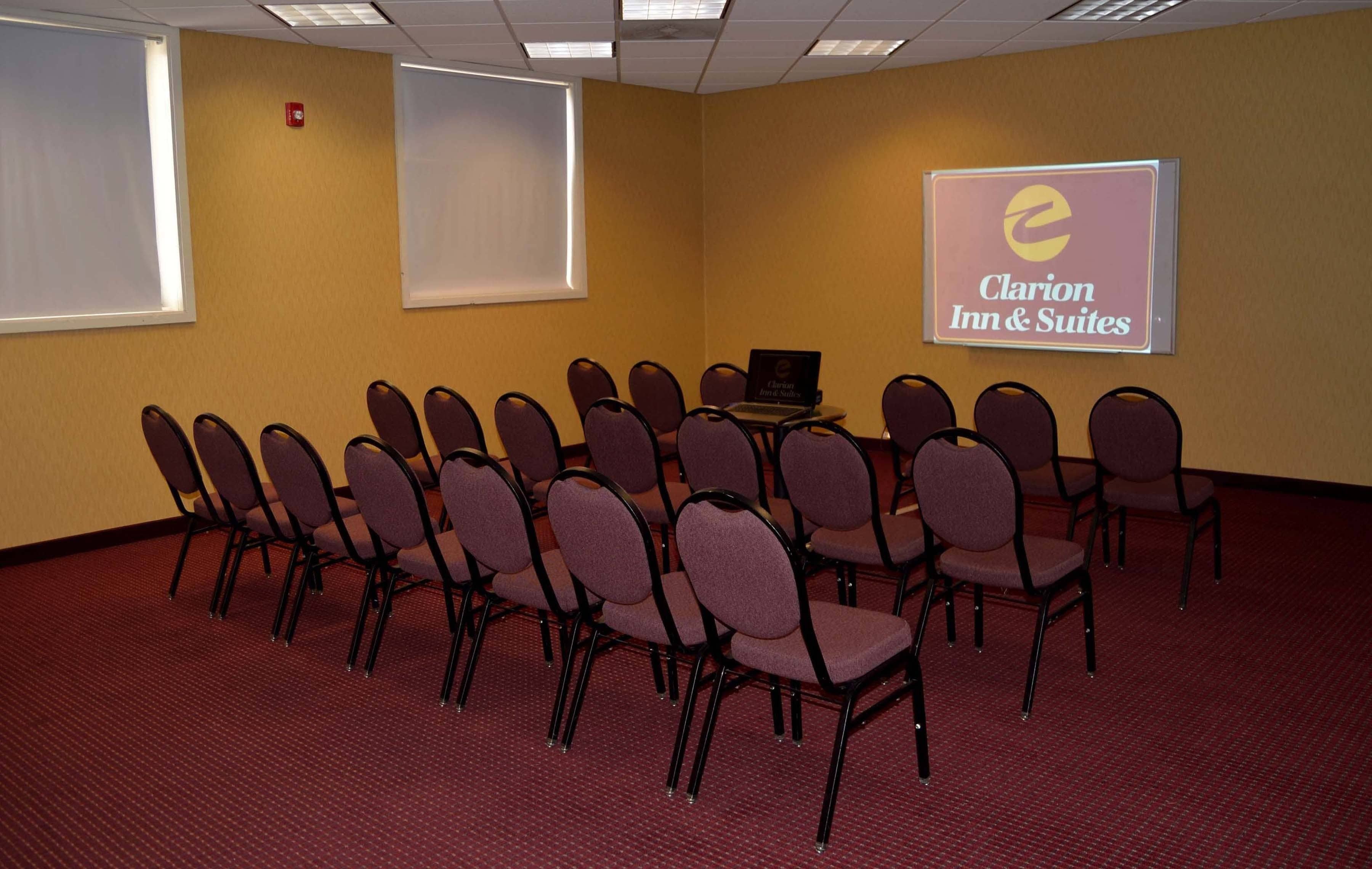 A conference room with rows of chairs, a projector screen, and a laptop on a table.
