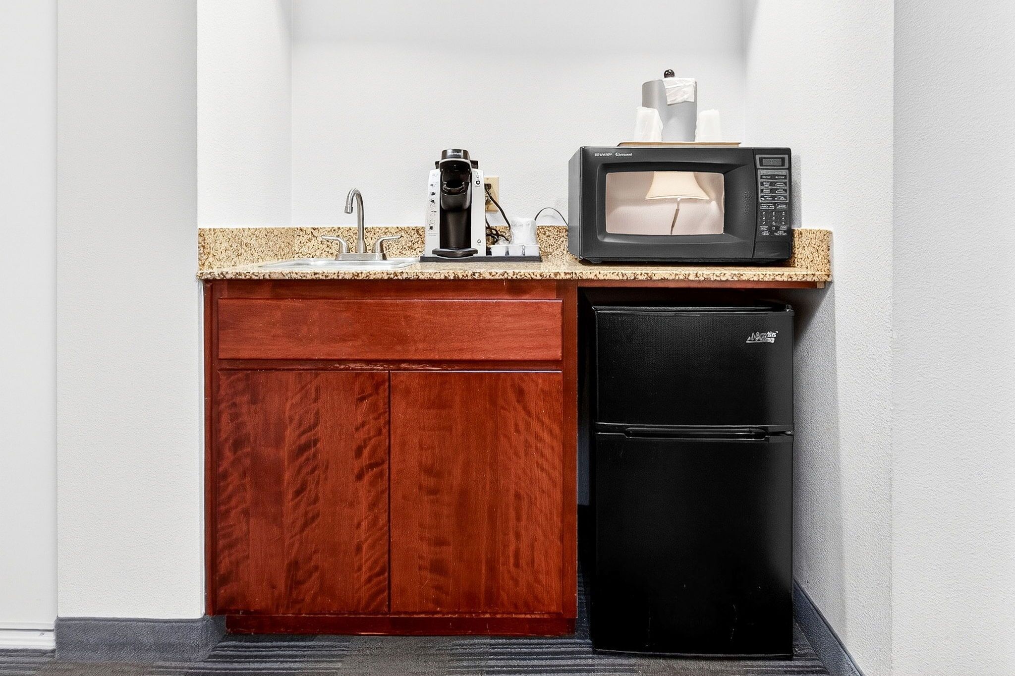 A compact kitchenette with a microwave, coffee maker, and refrigerator.