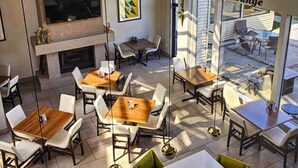 A modern indoor dining area with multiple tables and chairs, a fireplace, and a view of the outdoor seating area. - Holiday Inn Clarkston - Lewiston by IHG (Clarkston)