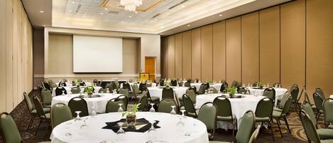 A conference room with multiple tables, chairs, and a large screen.