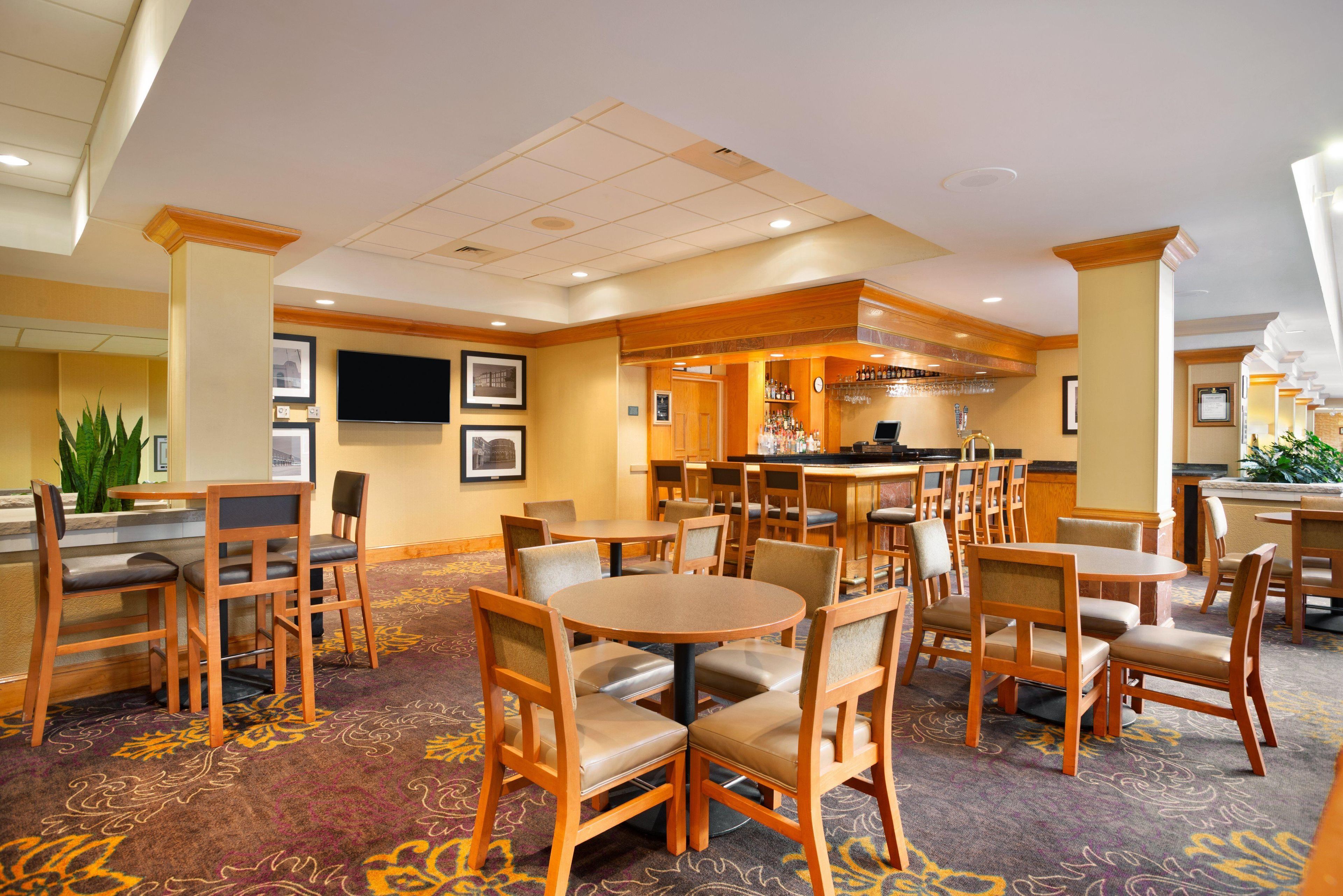 A hotel lobby with multiple seating areas, a bar, and a television screen.