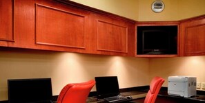 Una stanza con mobili in legno, una TV a schermo piatto e due postazioni computer.