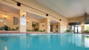 Una piscina interior con agua cristalina, rodeada de paredes color beige y equipada con luces empotradas.
