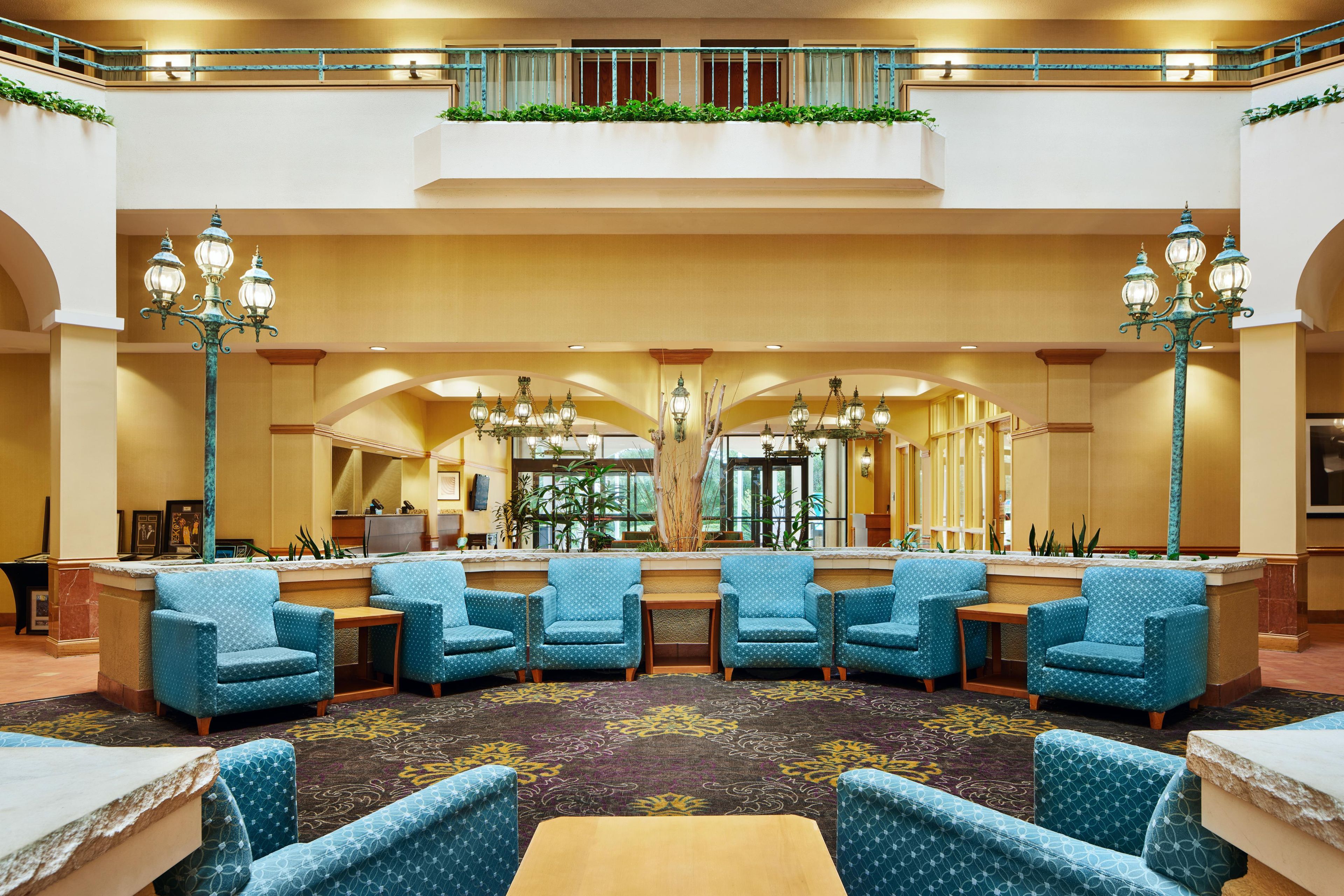 A lobby with a reception desk, seating area, and a staircase.