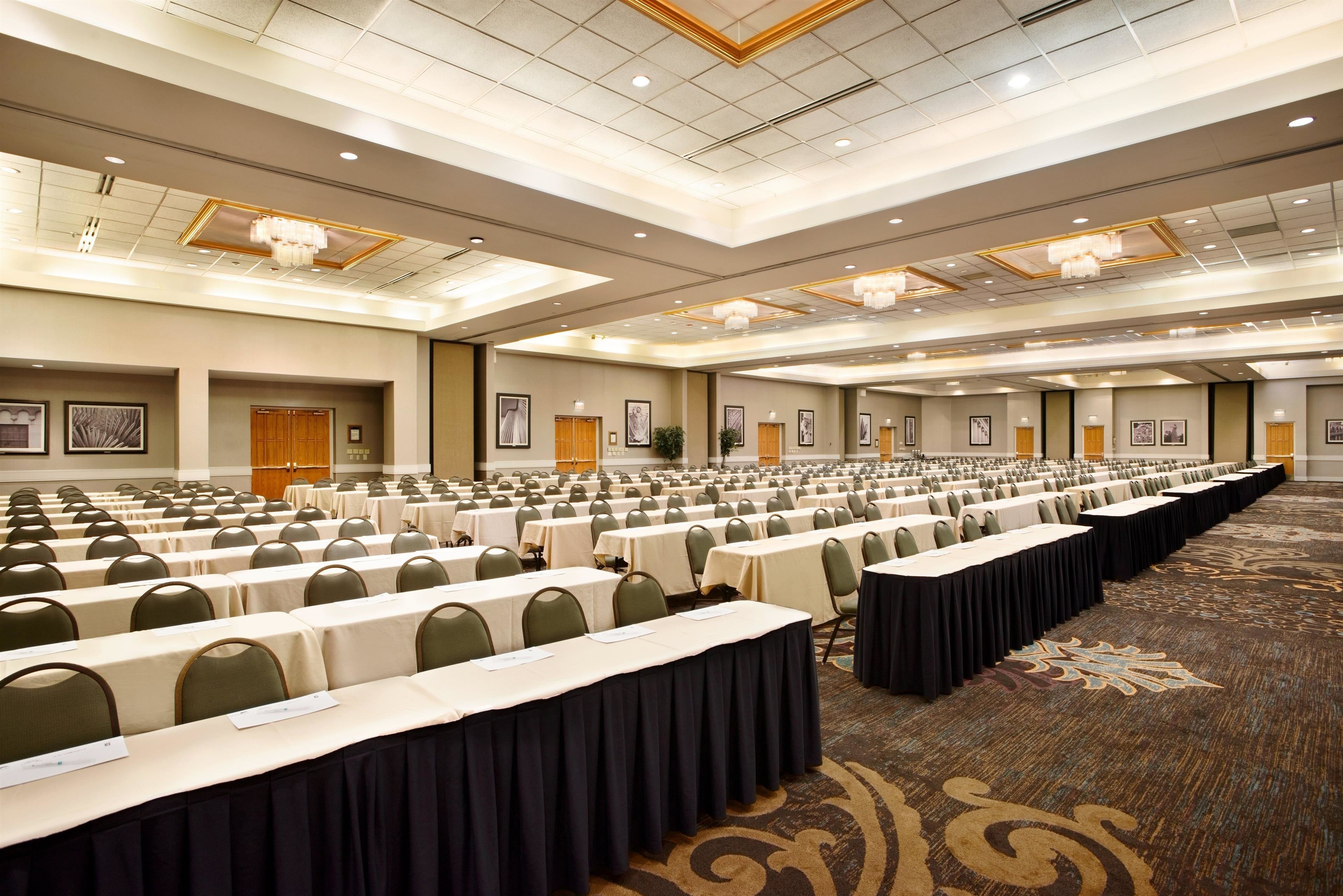 A large conference room with rows of tables and chairs, a carpeted floor, and framed pictures on the walls.