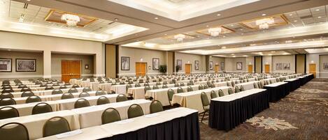 A large conference room with rows of tables and chairs, a carpeted floor, and framed pictures on the walls.