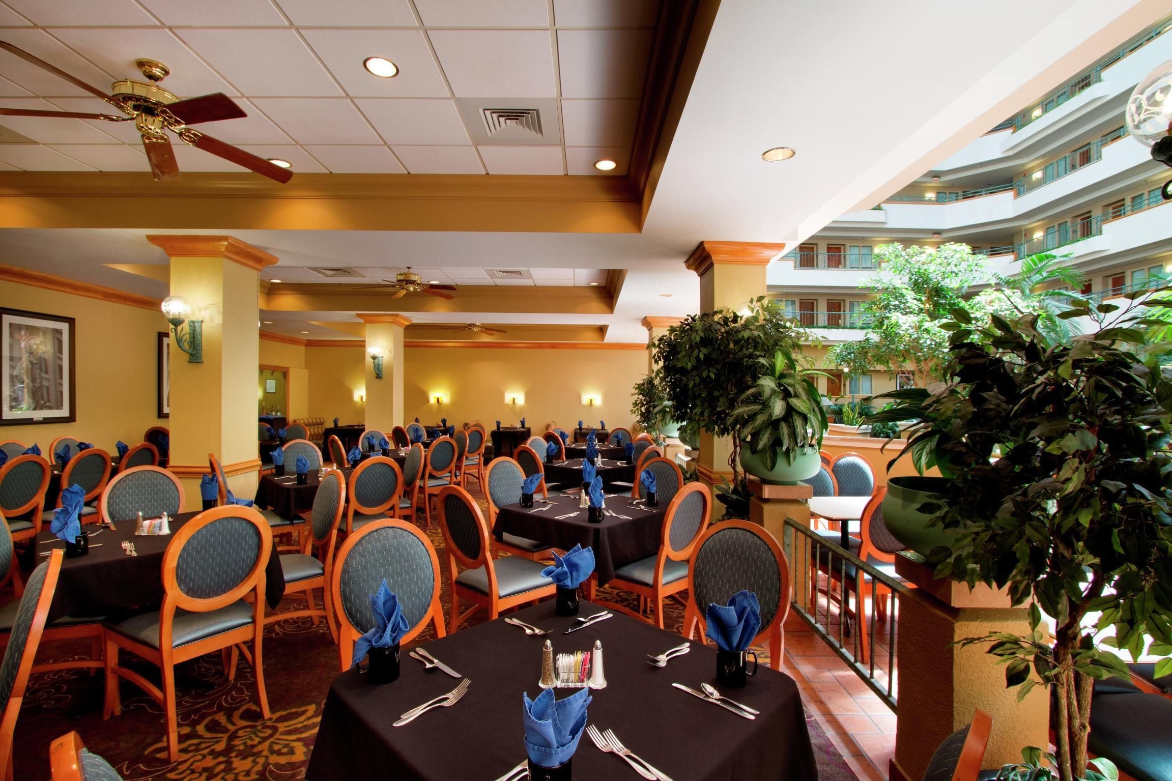Un comedor de hotel con varias mesas, sillas y ventiladores de techo.
