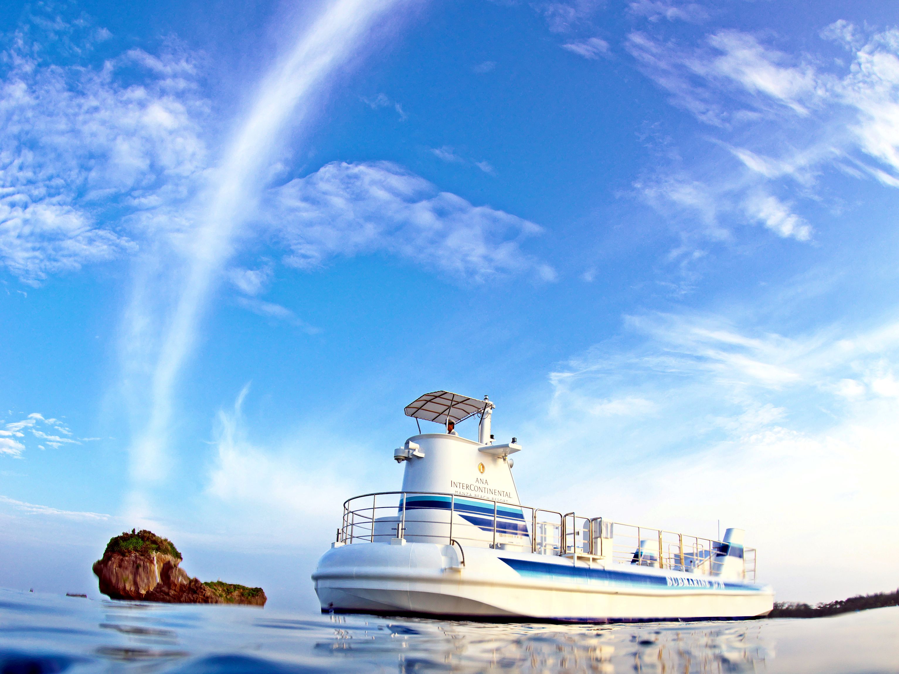 A white boat with blue stripes and a lighthouse on top, sailing on calm water.