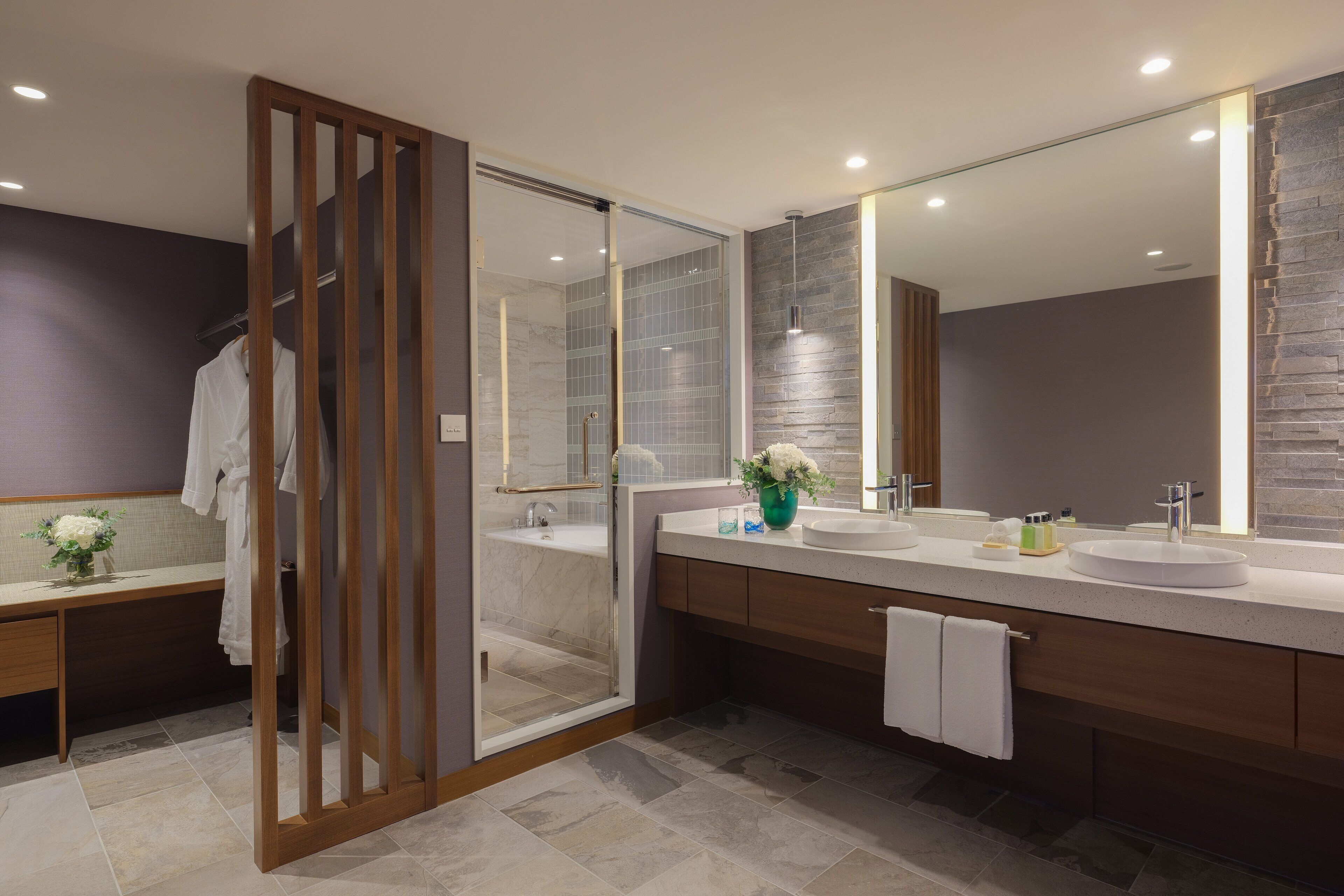 A modern bathroom with a glass shower enclosure, a large mirror, and a vanity with two sinks.