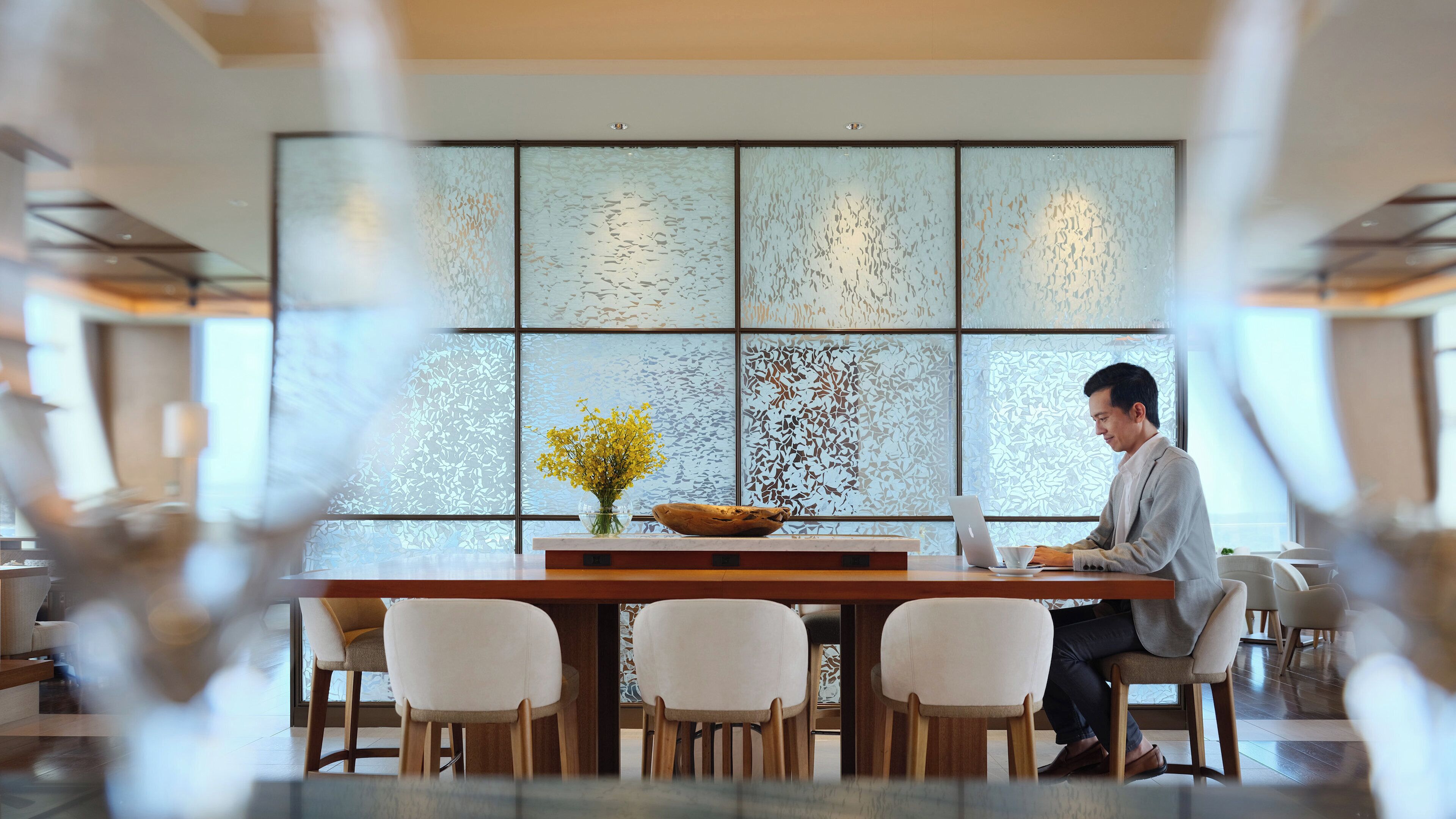 Un espace repas moderne, doté d’une grande table, de chaises et d’un mur décoratif.