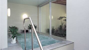 A spa area with a hot tub, a metal ladder, and potted plants.
