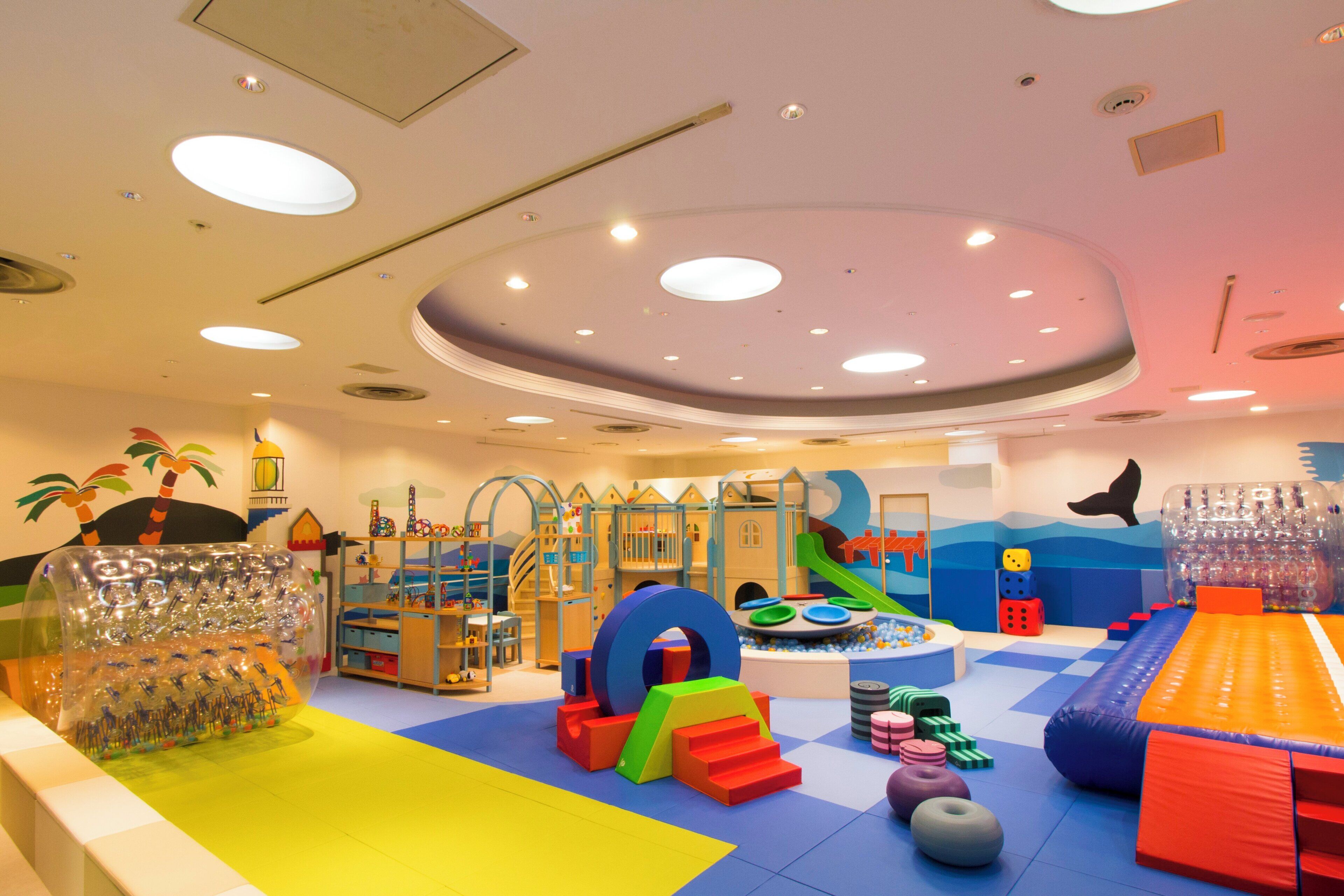 Ein Kinderspielbereich mit verschiedenen Spielgeräten, darunter eine Rutsche und Klettergerüste.