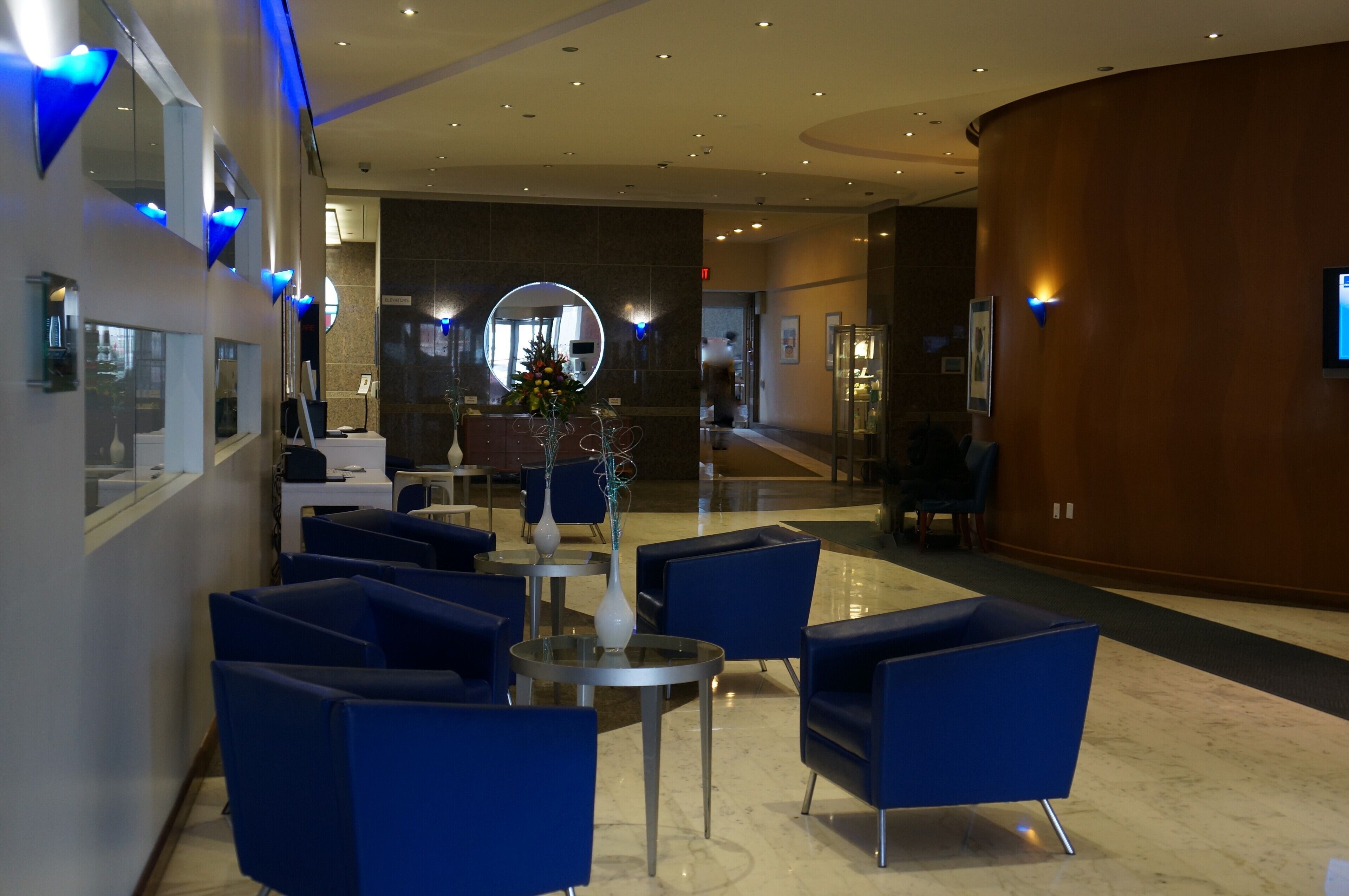A modern lobby with blue seating, a reception desk, and a large mirror.