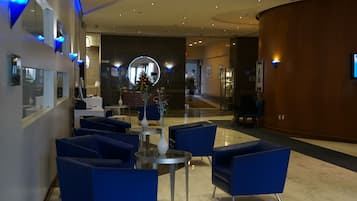 A modern lobby with blue seating, a reception desk, and a large mirror.