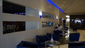 Un moderno vestíbulo de hotel con asientos azules, una recepción y una zona de bar.