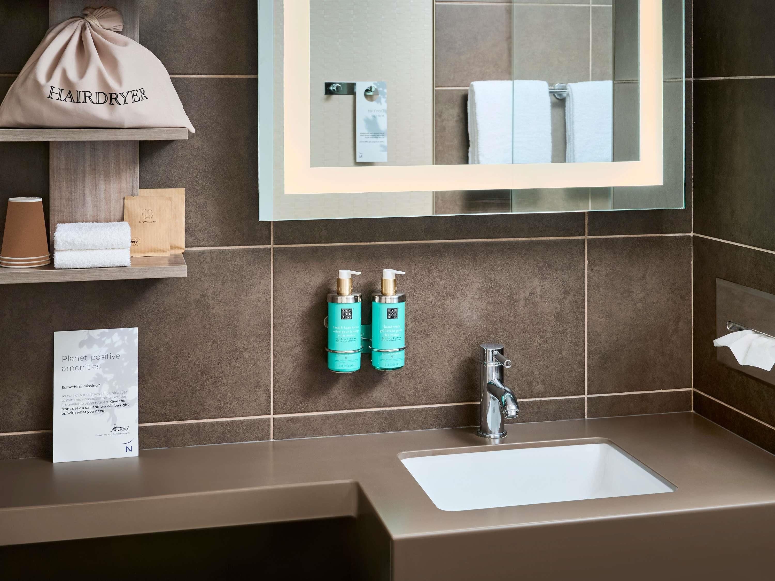 A bathroom with a sink, mirror, towel rack, and a bag labeled 'HAIRDRYER'.
