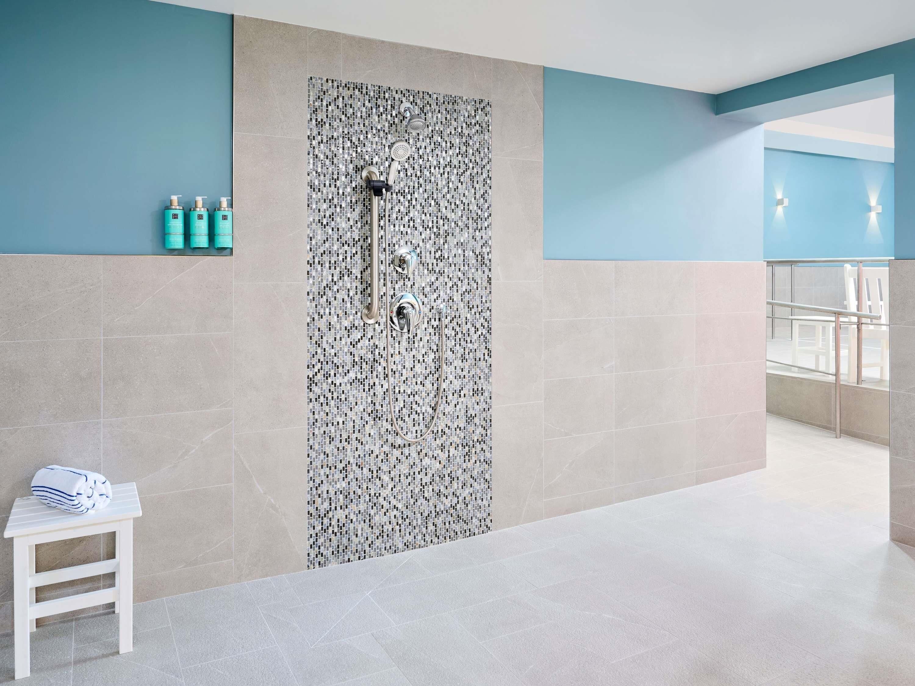 A modern bathroom with a shower, tiled walls, and a small table with towels.
