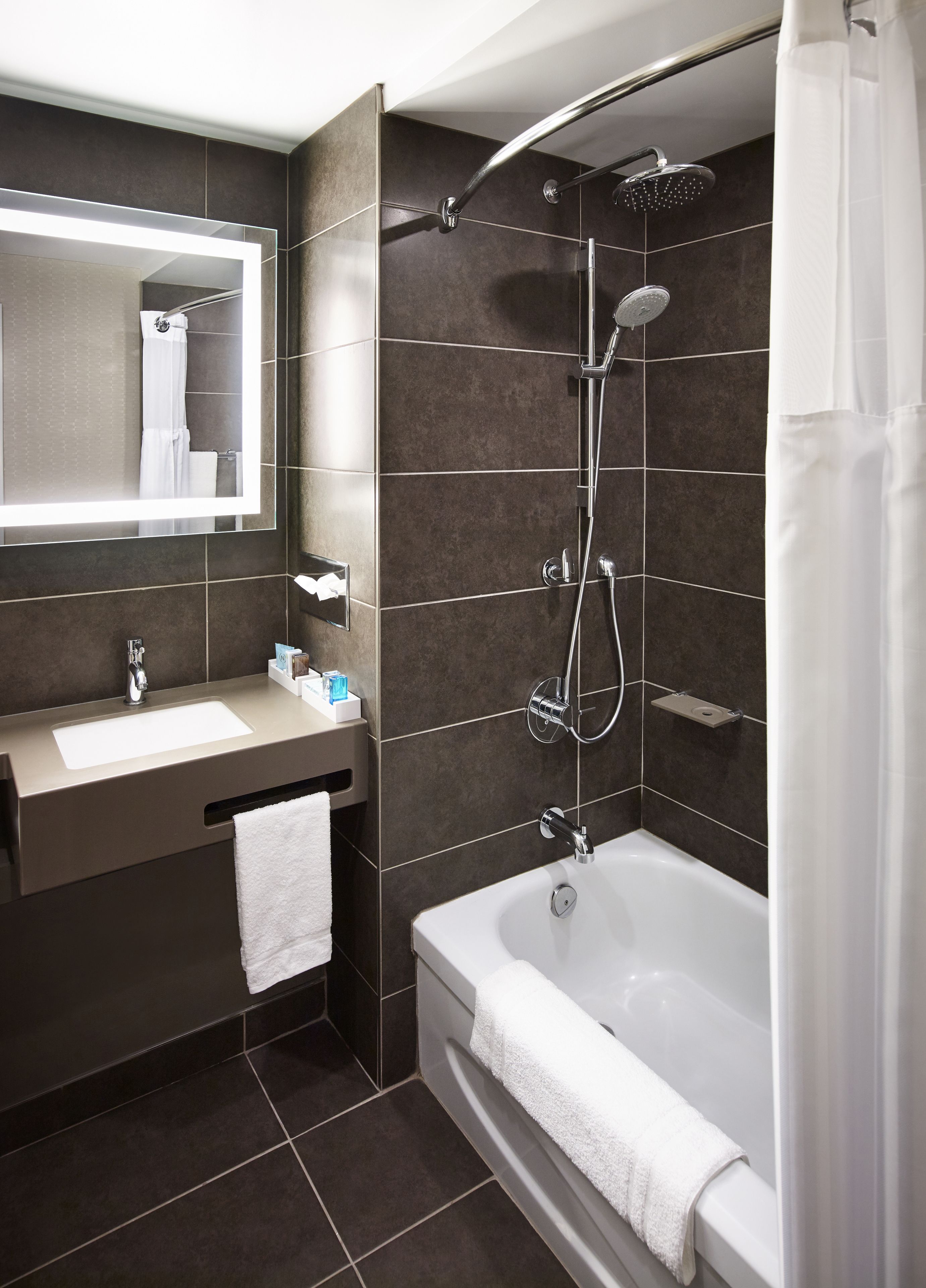 A modern bathroom with a large mirror, a sink, a bathtub, and a shower.