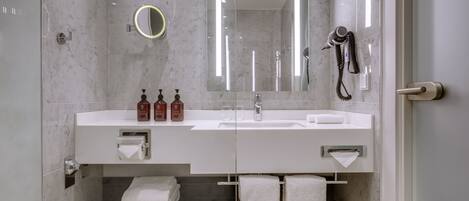 Un baño moderno con un espejo grande, un secador de pelo y un perchero para toallas.