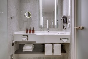 Un baño moderno con un espejo grande, un secador de pelo y un perchero para toallas.
