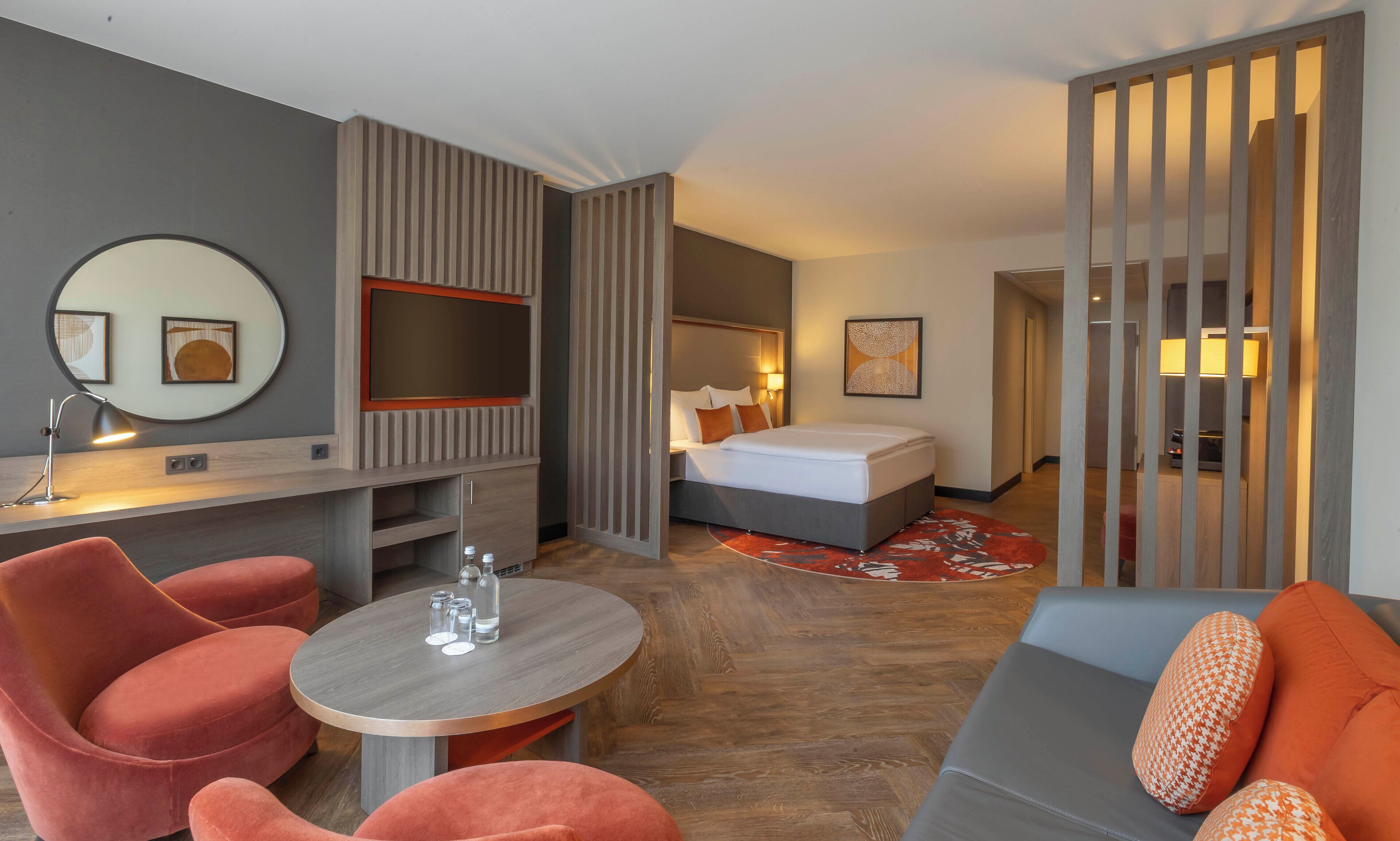 Una habitación de hotel moderna con cama, escritorio, silla y sofá.